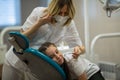 Dentist  doing teeth checkup of little girl looking with fear sitting in stomatology clinic Royalty Free Stock Photo