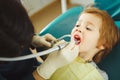 Dentist drills tooth to small boy, calm child in doctor`s chair suffers pain.