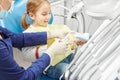 Dentist educating a little girl about proper tooth-brushing, demonstrating on a model.