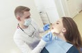 dentist examines the patient's mouth at a clinic appointment