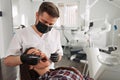 Dentist examining patient teeth with a mouth mirror and dental excavator. Close-up view on the woman`s face Royalty Free Stock Photo