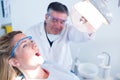 Dentist examining a patients teeth in chair under bright light Royalty Free Stock Photo