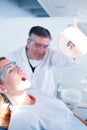 Dentist examining a patients teeth in chair under bright light Royalty Free Stock Photo