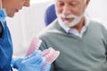 Dentist explaining procedure to patient on plastic jaw model