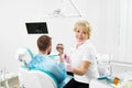 Dentist female holding tool, near sits patient looks in mirror