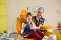 a dentist girl shows a child a mock-up of a jaw.