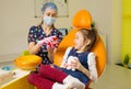 a dentist girl shows a child a mock-up of a jaw.