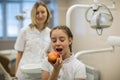 Dentist gives apple for teenage girl in dental clinic