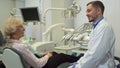 Dentist greets female client at his office