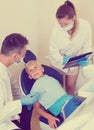 Dentist guy with assistant are diagnosticating to young patient