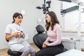 Dentist holding dental articulator with dental gypsum prosthesis model showing it to a patient