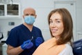A dentist is holding a dental mirror and dental explorer near a female patient Royalty Free Stock Photo