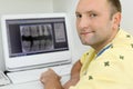 Dentist looks at camera and sits with teeth X-rays