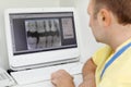 Dentist looks at teeth X-rays at computer monitor Royalty Free Stock Photo