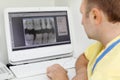 Dentist looks at teeth X-rays at computer monitor