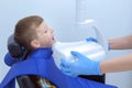 Dentist making x-ray of teeth for teenage boy child in dental clinic, side view.