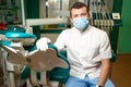 Dentist in mask doctor sits in his office