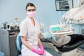 Dentist with patient in the dental office. Doctor wearing glasses, mask, white uniform and pink gloves Royalty Free Stock Photo