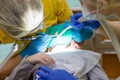 Dentist performing dental filling procedure to preteen girl in pediatric dental clinic. Doctor removing caries using