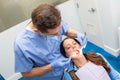 Dentist performing teeth treatment with female patient open mouth