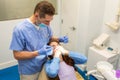 Dentist performing teeth treatment with scared female patient