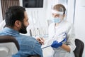 Dentist in protective mask talking her male patient Royalty Free Stock Photo