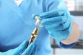 Dentist putting crown onto abutment of dental implant on blurred background, closeup