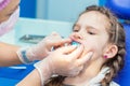 Dentist putting orthodontic trainer for little girl sitting on chair in Dentist office