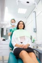 The dentist's assistant puts the protection on the patient, the napkin on the chest