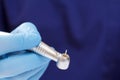 Dentist`s hand in glove with dental handpiece