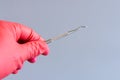 dentist's hand holding dental tools in silhouette grey background. Dentist's hand in red glove with a tool