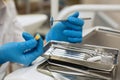 Dentist`s hands holding yellow tooth and dental tools in dental clinic.