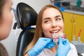 Dentist selects a shade of teeth whitening using shade guide to young patient with perfect smile Royalty Free Stock Photo