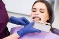 Dentist selects a shade of teeth whitening using shade guide to young woman with perfect smile. Royalty Free Stock Photo