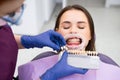 Dentist selects a shade of teeth whitening for young woman with perfect smile Royalty Free Stock Photo