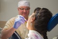 The dentist shines a UV light seal to a woman in a private clinic