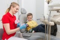 The dentist showing the little boy how to clean the teeth with a toothbrush on an artificial jaw dummy