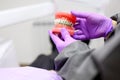 Dentist showing to patient an orthodontics dental model, explaining to patient the orthodontics treatment in dental