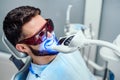 Dentist starting teeth whitening procedure with young man Royalty Free Stock Photo