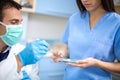 Dentist takes dental filling prepared by his assistant