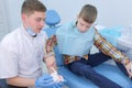 Dentist teaching child boy how to clean teeth using toy jaw model.