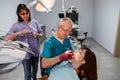 Dentist team, elderly man and woman, and young female patient having professional treatment in modern dental office Royalty Free Stock Photo