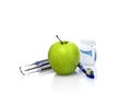 Dentist tools and fresh green apple with water drops isolated on white background in dental office. Dental care concept. Royalty Free Stock Photo