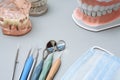 Dentist tools, medical mask and artificial jaws on a blue background