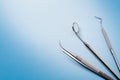 Dentist tools: mirror, dental explorer and tweezers in right on blue gradient background
