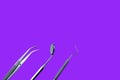 Dentist tools: mirror, dental probe and tweezers on purple background