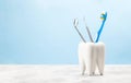 Dentist toothbrush and steel tools mirror and hook in tooth shaped glass. Blue background Royalty Free Stock Photo