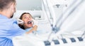 Dentist is treating female patient which is sitting in dental chair Royalty Free Stock Photo