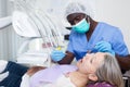 Dentist is treating female patient which is sitting in dental chair in clinic Royalty Free Stock Photo