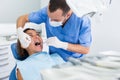 Dentist is treating female patient which is sitting in dental chair Royalty Free Stock Photo